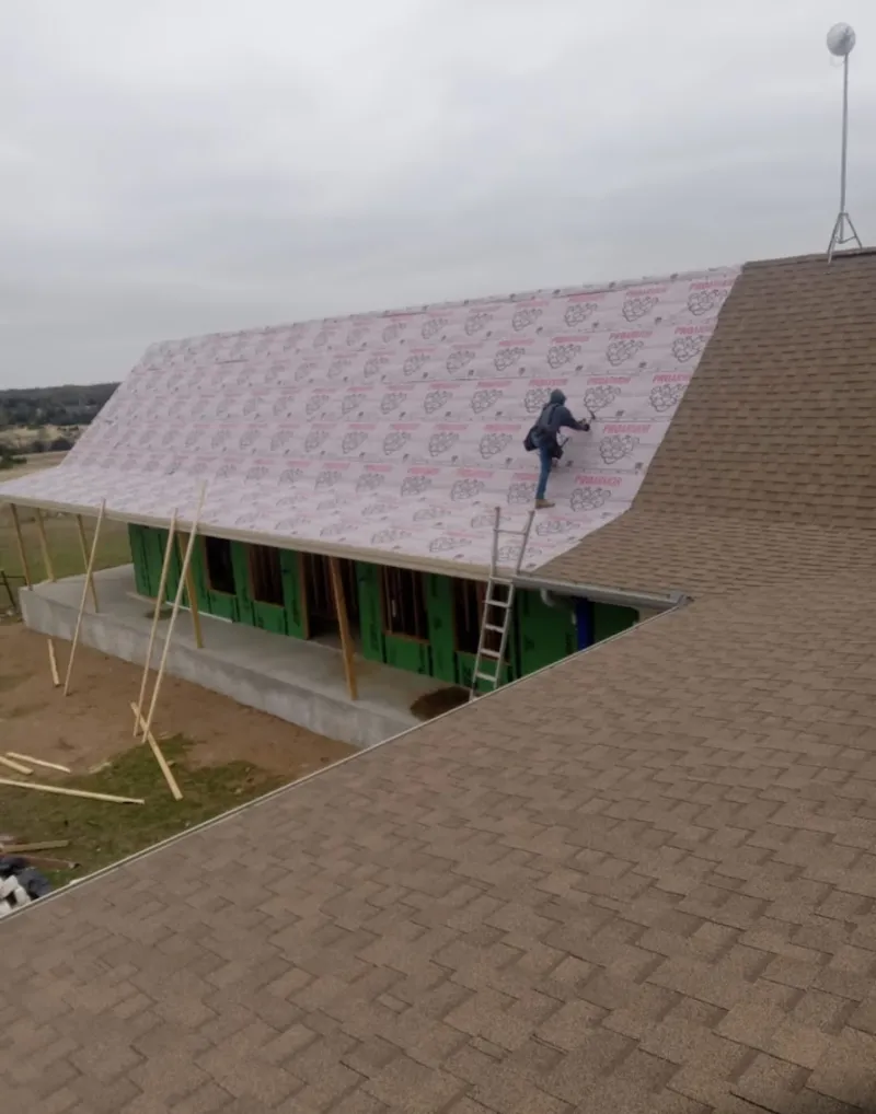 Worker preparing underlayment for a metal roof installation in Menomonee Falls